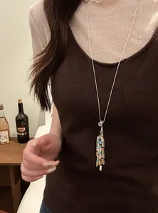 Close-up detail of a bohemian beaded tassel necklace worn over a brown knitted top
