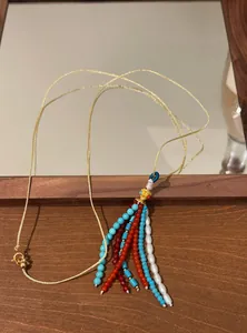 Macro view of bohemian beaded tassel with turquoise beads and pearls on necklace