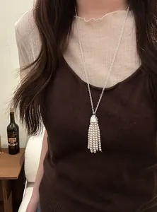 Close-up of elegant bohemian pearl tassel necklace worn over a brown knit sweater