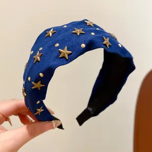 Close-up of a stylish blue fabric headband featuring gold star-shaped metal studs.