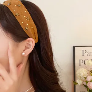 Close-up detail of brown fabric headband with vintage metal star studs decoration