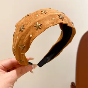 Close-up of a brown suede headband with vintage gold star and stud embellishments.