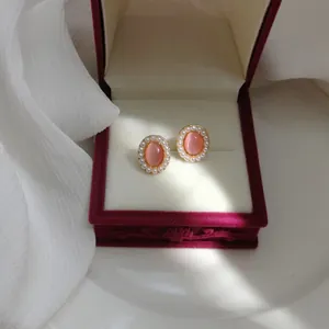 Elegant pink cat's eye stud earrings with pearl border inside a velvet jewelry gift box