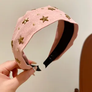 Close-up of pink fabric headband featuring stylish gold star and stud decorations