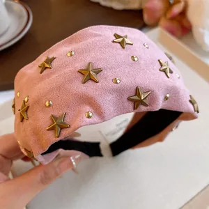Close-up of pink fabric headband with gold star studs and high-quality texture detail.