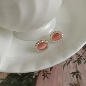Elegant close-up of vintage pink cat-eye stone stud earrings with white pearl halo