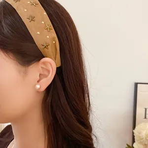 Detailed view of a khaki fabric headband decorated with gold star studs on an Asian model