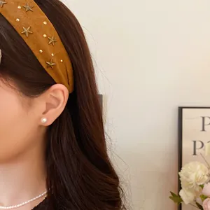 Close-up of a stylish brown fabric headband with gold star studs on a model