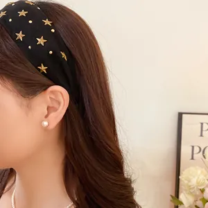 Detailed side view of a black fabric headband featuring golden star studs on a model