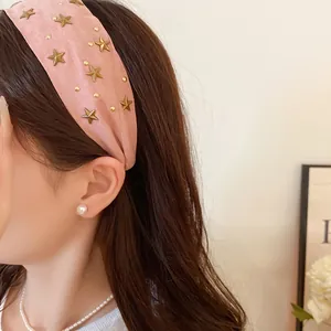 Side view detail of a pink fabric headband with gold star studs worn by a woman