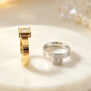 Primo piano di anelli in acciaio inossidabile oro e argento con pietre di zircone quadrate