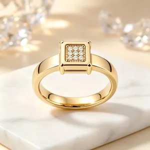 Dettaglio ravvicinato di un anello in acciaio dorato con una montatura quadrata a nove cristalli.