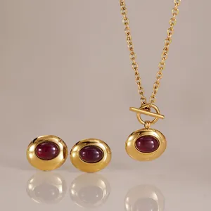 Elegantes goldfarbenes Schmuckset mit tiefroter Harz-Halskette und passenden Ohrsteckern.