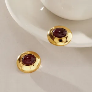 Nahaufnahme von vintage Edelstahl-Ohrsteckern in Gold mit dunkelrotem Harz-Inlay.
