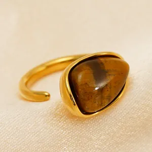 Nahaufnahme eines goldenen Edelstahlrings mit einem polierten Tigerauge-Edelstein