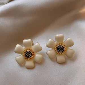 Detailed view of French vintage enamel flower earrings with creamy white petals and gold core