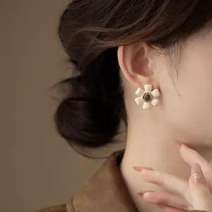 Close-up of a French vintage cream enamel flower stud earring on an Asian model.