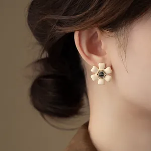 Close-up of vintage French cream flower earring with oil-dripping detail on model's ear