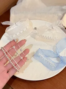 Detailansicht handgehaltener koreanischer Perlenarmbänder mit Organzabändern und Kristallen.