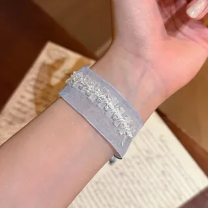 Nahaufnahme eines eleganten blauen Gazearmbands mit weißen Perlen auf dem Handgelenk.