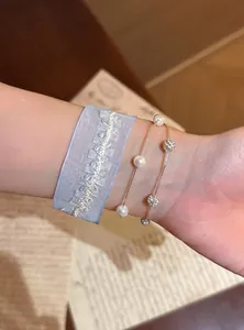 Detailansicht eines eleganten Armbands mit Organzaband und Perlenperlen