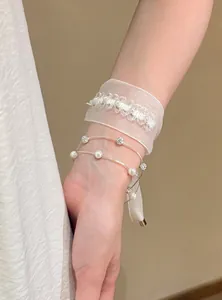 Elegante Detailansicht eines koreanischen Armbands aus weißem Organza und Perlen am Handgelenk
