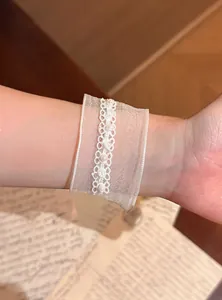 Detailaufnahme eines eleganten weißen Schneegarn-Armbands mit Perlen und Spitze