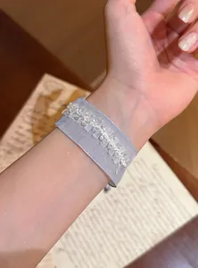 Nahaufnahme eines zarten hellblauen Organza-Armbands mit weißer Perlenstickerei am Handgelenk