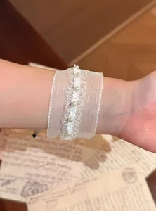 Primo piano di un braccialetto di perle in organza bianca con sfondo vintage