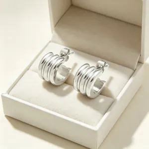 Close-up of minimalist stainless steel triple hoop C-shaped earrings inside a white gift box.