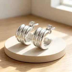 Close-up detail of minimalist triple-layered stainless steel C-shaped hoop earrings