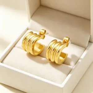Detailed macro view of gold-plated triple-layer C-shaped hoop earrings in a jewelry box
