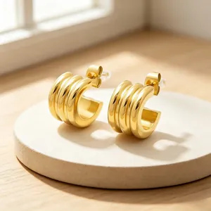 Detailed macro view of minimalist gold-plated triple-layer curved C-shape hoop earrings