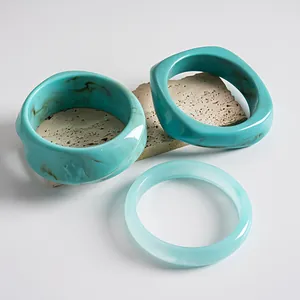 Gedetailleerde weergave van drie blauwe acryl armbanden met marmering op een steen