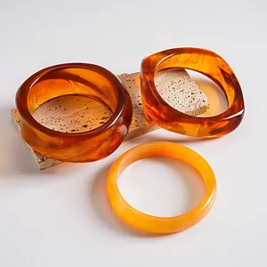 Detailweergave van amberkleurige acryl armbanden met gemarmerde patronen en gladde afwerking