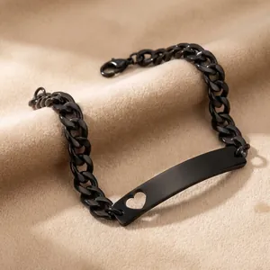 Primer plano de pulsera de cadena cubana negra con placa metálica curva y recorte de corazón