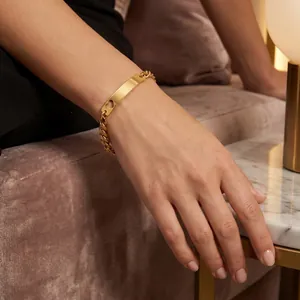 Vista detallada de una pulsera de acero de titanio dorado con placa de corazón y cadena.