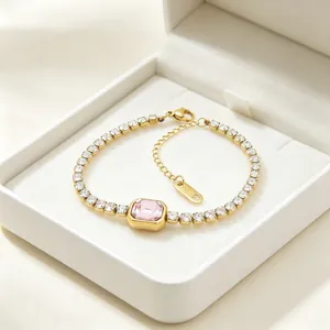 Dettaglio di un bracciale tennis dorato con una gemma rosa rettangolare centrale.