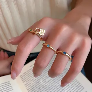 Vintage gold ring set with colorful zircon stones and engraved tag on a woman's hand