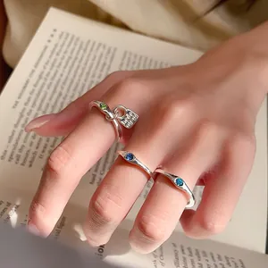 Close-up of a silver vintage ring set with blue and green crystals displayed on a hand.