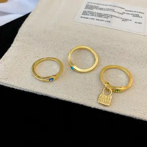 Detailed macro shot of vintage gold rings featuring vibrant zircons and a lock charm on a pouch