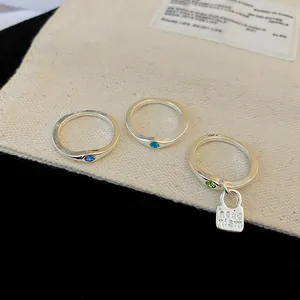 Detailed view of three vintage silver rings with blue and green stones and charm