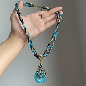 Gros plan d'un collier pendentif goutte vintage avec cordon tressé bleu et strass