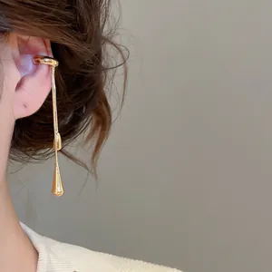 Detailed view of an elegant gold water drop tassel ear cuff worn on a minimalist ear bone