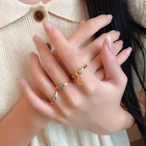 Detail of retro gold rings set with blue and green gems and a small lock charm