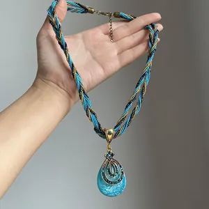 Gros plan détaillé d'un collier tissé bohème doté d'un pendentif goutte turquoise