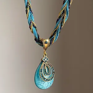 Détail macro du collier avec pendentif goutte d'eau turquoise et cristaux bleus.