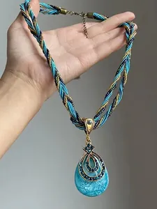 Vue détaillée du pendentif goutte turquoise vintage avec cordon tressé bleu et doré