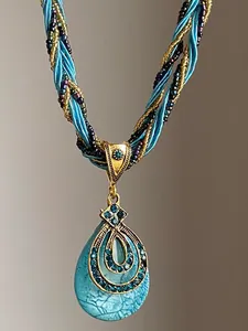 Vue détaillée d'un collier avec pendentif goutte bleue vintage et strass dorés