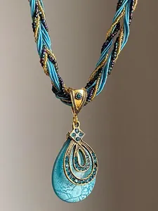 Détail d'un collier pendentif goutte d'eau bleue avec strass et cordon tressé élégant